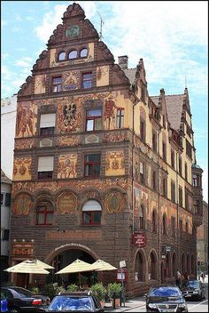 an old building with many windows on the front and side of it, along with parked cars