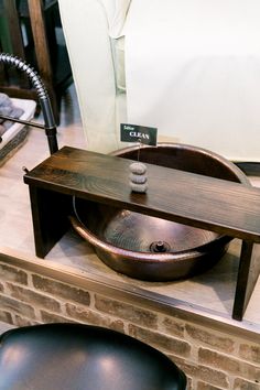 a wooden sink sitting on top of a counter next to a black chair and table