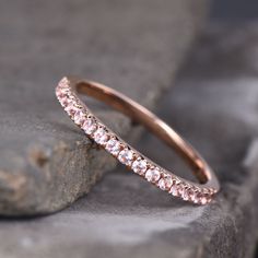 a pink diamond wedding band on top of a rock