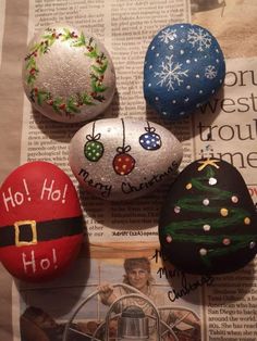 four decorated rocks sitting on top of a newspaper