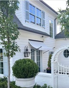 a white house with a large potted planter in front of it and an awning over the door