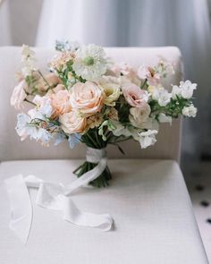 a bouquet of flowers sitting on top of a white chair next to a ribbon tied around it