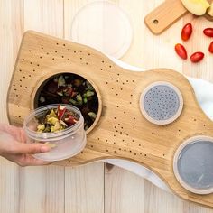 a person holding a container with food in it on top of a wooden cutting board