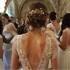 the back of a woman's wedding dress with gold leaves on her head and shoulders