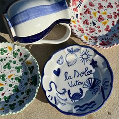 three plates with different designs on them sitting next to each other, one has the words la dolce vita written on it