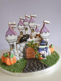 a cake that is decorated to look like a castle with pumpkins and witches on it