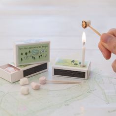 a person lighting a match with marshmallows next to it