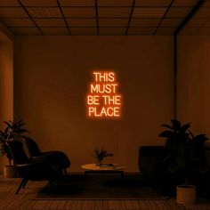 a neon sign that reads, this must be the place with two chairs and a coffee table