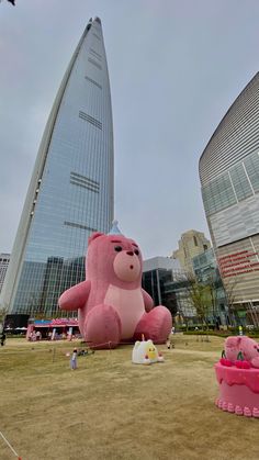 there is a giant pink teddy bear in front of some buildings and children's toys