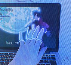 a person is typing on a laptop with their hand in front of the screen and an image of a man holding a doll