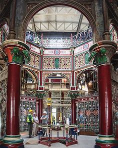 two men are standing in the middle of a room with red pillars and ornate decorations