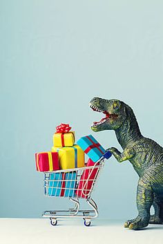 a toy dinosaur pushing a shopping cart full of presents