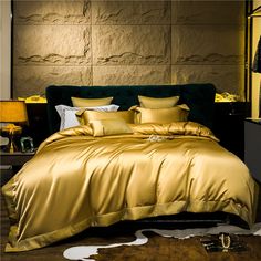 a bed with gold comforter and pillows in a luxurious bedroom setting on the floor