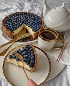 there is a pie with blueberries on it and a cup of tea