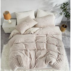 a bed with white fluffy blankets and pillows on top of it, next to a lamp