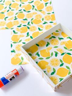 an open box with yellow lemons on it next to a tube of glue and paper