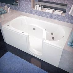 a bathroom with a white bath tub sitting next to a blue rug