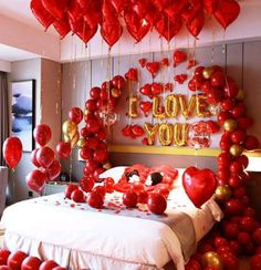 a bed with lots of red and gold balloons floating from it's headboard