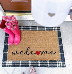 a welcome mat with pink boots and flowers on the front porch next to a woman's boot