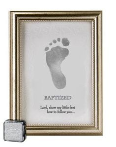 a baby's foot is shown in a gold frame with a small metal object next to it