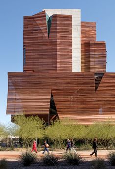 people walking in front of a large building with wooden slats on it's side