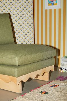 a green chair sitting on top of a rug next to a wallpapered wall