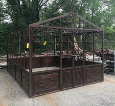 a metal structure sitting in the middle of a parking lot next to trees and bushes