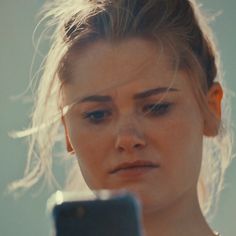 a close up of a person holding a cell phone in front of her face and looking at the screen