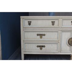 a white dresser with drawers and knobs on it's sides in a room