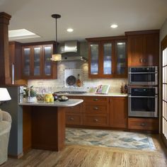 a large kitchen with wooden cabinets and stainless steel appliances in the center, along with hardwood flooring