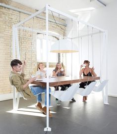 a group of people sitting around a table in a room with white walls and windows