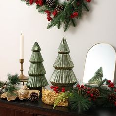 christmas decorations with pine cones and evergreens on a table in front of a mirror