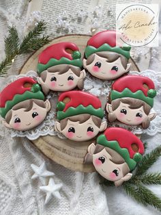 christmas cookies decorated with elf faces and green hats on top of a lace doily