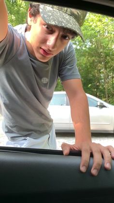 a young man holding his hand out the window of a car