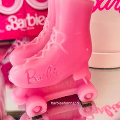 pink roller skates with name on them sitting next to each other in front of barbie's shoes