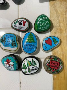 six painted rocks with christmas designs on them sitting on a tile floor next to each other