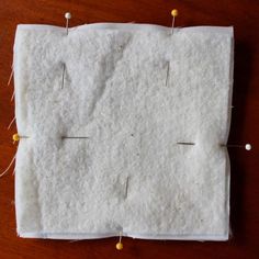 a piece of white fabric with pins on it and some thread in between the pieces