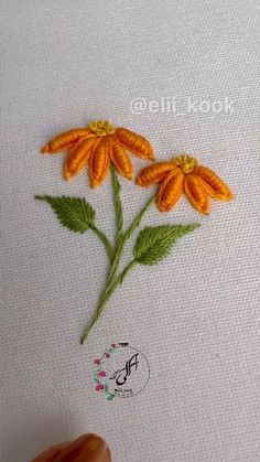 someone is stitching flowers on a piece of fabric