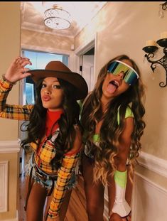 two women dressed up in costumes and hats posing for the camera with their tongue out