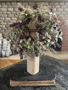 a vase filled with purple flowers sitting on top of a table next to a book