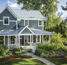 a blue house with white trim on the front and side of it, surrounded by trees