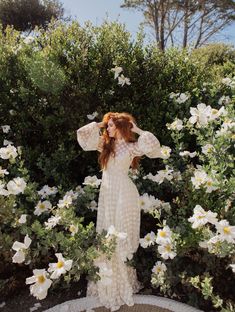 a woman is standing in front of some flowers