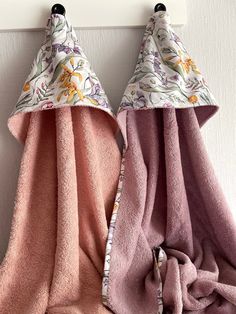 two towels are hanging on a hook next to each other, one has a pink and purple flowered towel