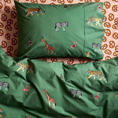 two green pillows with zebras and giraffes on them sitting next to each other