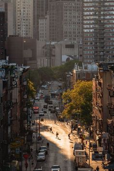 a city street with cars and people skating on the road in front of tall buildings