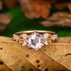 a pink diamond ring sitting on top of a leaf