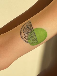 a person with a green apple tattoo on their arm and the image of a slice of fruit