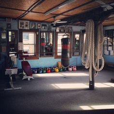 an empty gym room with ropes hanging from the ceiling and other equipment on the floor