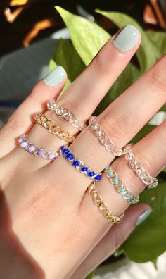 a woman's hand with five different rings on her fingers and one is wearing a ring