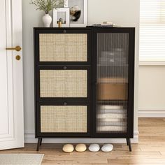 a black cabinet with wicker doors and baskets on the bottom, in front of a white door